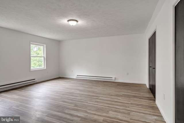 121 Almond Ct, Milford, PA 18337 - empty room featuring a baseboard heating unit, a textured ceiling, and wood finished floors
