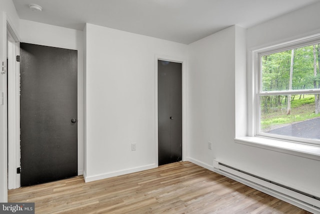 121 Almond Ct, Milford, PA 18337 - unfurnished bedroom with baseboard heating, light wood-type flooring, and multiple windows