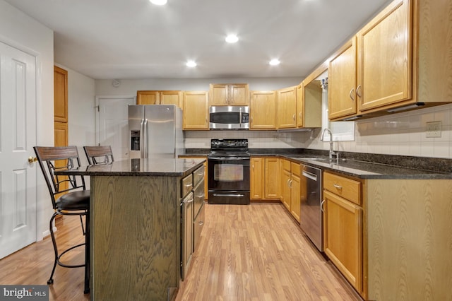5 Michael Ct, Rehoboth Beach, DE 19971 - kitchen with stainless steel appliances, a breakfast bar, light wood-style flooring, tasteful backsplash, and a center island