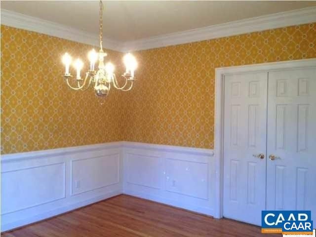 3190 Prestwick Pl, Keswick, VA 22947 - unfurnished dining area featuring a chandelier, wainscoting, wallpapered walls, ornamental molding, and wood finished floors