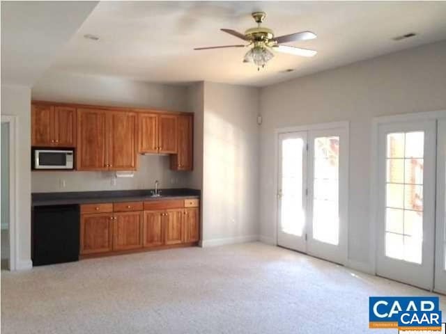 3190 Prestwick Pl, Keswick, VA 22947 - kitchen featuring brown cabinetry, dishwashing machine, dark countertops, a ceiling fan, and light colored carpet