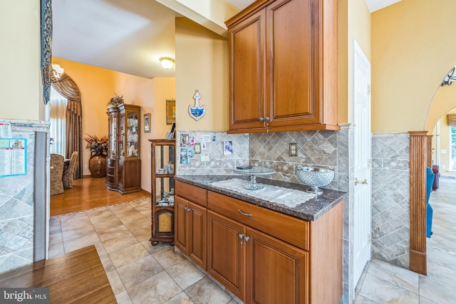 15 Kresson Ct, Berlin, NJ 08009 - kitchen featuring arched walkways, brown cabinetry, dark stone counters, and tasteful backsplash