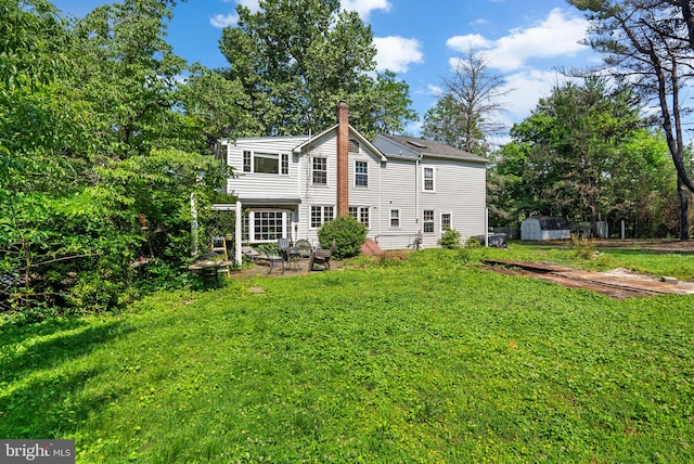 13321 Travilah Rd, Potomac, MD 20854 - rear view of house with a chimney, a lawn, and a patio area