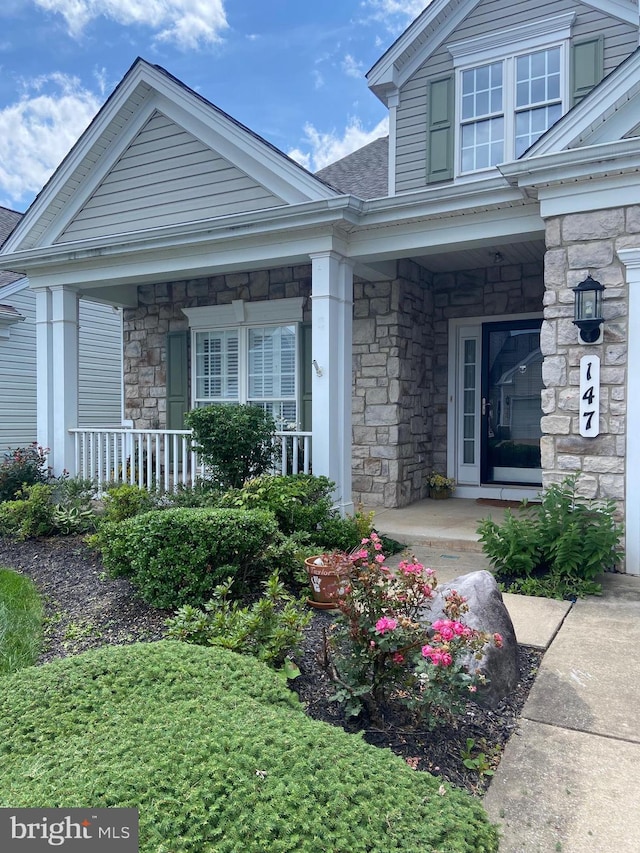 147 Saddletop Dr Unit 381, Taneytown, MD 21787 - view of exterior entry with covered porch, stone siding, and roof with shingles