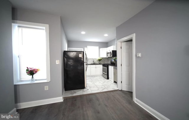 3124 N Carlisle St, Philadelphia, PA 19132 - kitchen with stainless steel appliances, white cabinets, dark countertops, light wood-style flooring, and tasteful backsplash