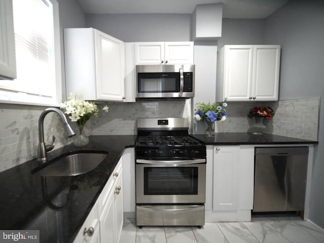 3124 N Carlisle St, Philadelphia, PA 19132 - kitchen with appliances with stainless steel finishes, light marble finish floors, white cabinetry, dark stone countertops, and backsplash