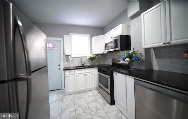 3124 N Carlisle St, Philadelphia, PA 19132 - kitchen with appliances with stainless steel finishes, light marble finish floors, dark countertops, white cabinets, and backsplash