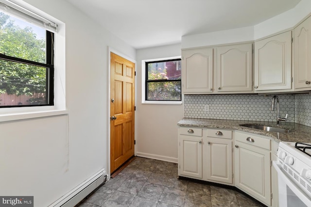 1615 S 16th St, Philadelphia, PA 19145 - kitchen featuring white gas range, decorative backsplash, light stone counters, baseboard heating, and stone finish flooring
