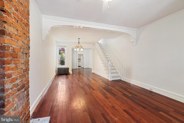 1615 S 16th St, Philadelphia, PA 19145 - unfurnished living room featuring radiator, arched walkways, wood-type flooring, stairs, and brick wall