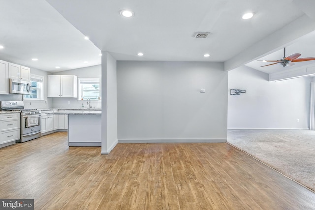 83 Morton Dr, Manahawkin, NJ 08050 - kitchen with appliances with stainless steel finishes, lofted ceiling, open floor plan, white cabinets, and light wood-style flooring