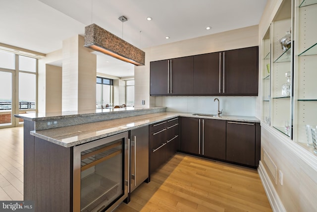 130 S 18th St Unit 3102, Philadelphia, PA 19103 - kitchen featuring wine cooler, dark brown cabinets, light wood-style floors, a peninsula, and recessed lighting
