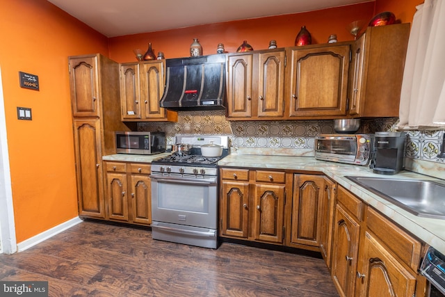 2212 S Bouvier St, Philadelphia, PA 19145 - kitchen featuring stainless steel appliances, extractor fan, light countertops, dark wood finished floors, and brown cabinets