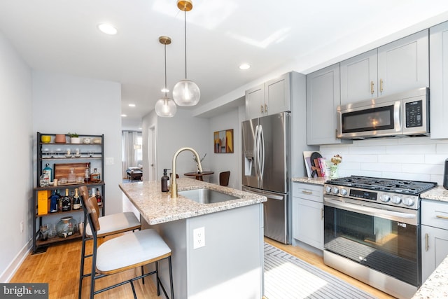 1229 S Bucknell St, Philadelphia, PA 19146 - kitchen with appliances with stainless steel finishes, gray cabinets, light wood-type flooring, backsplash, and light stone countertops