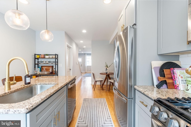 1229 S Bucknell St, Philadelphia, PA 19146 - kitchen featuring stainless steel appliances, light wood-type flooring, recessed lighting, hanging light fixtures, and light stone counters