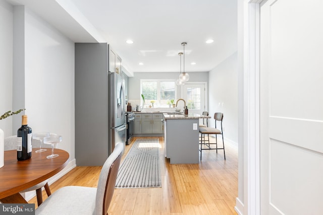 1229 S Bucknell St, Philadelphia, PA 19146 - kitchen with gray cabinetry, light wood-style flooring, a breakfast bar area, a kitchen island with sink, and recessed lighting