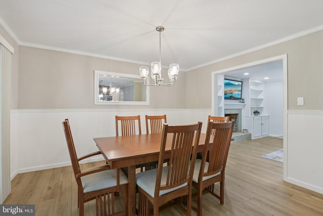 611 Hillcrest Dr, Perkasie, PA 18944 - dining room with wainscoting, light wood-style floors, ornamental molding, a chandelier, and a fireplace with raised hearth