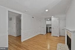 3241 N St NW Unit 1, Washington, DC 20007 - unfurnished living room featuring a fireplace, light wood-style flooring, crown molding, recessed lighting, and a decorative wall