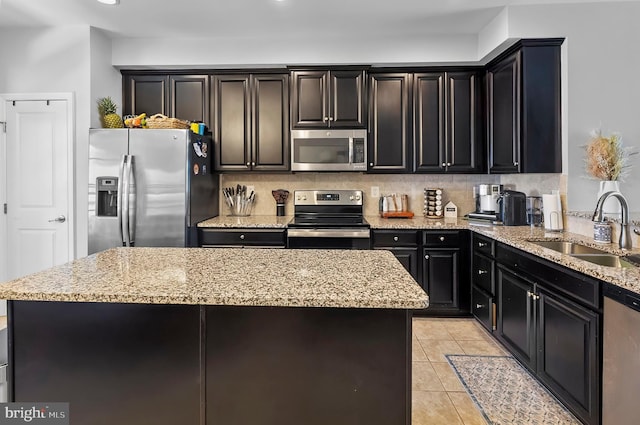 922 S Macon St, Baltimore, MD 21224 - kitchen featuring stainless steel appliances, light stone counters, decorative backsplash, dark cabinets, and light tile patterned floors