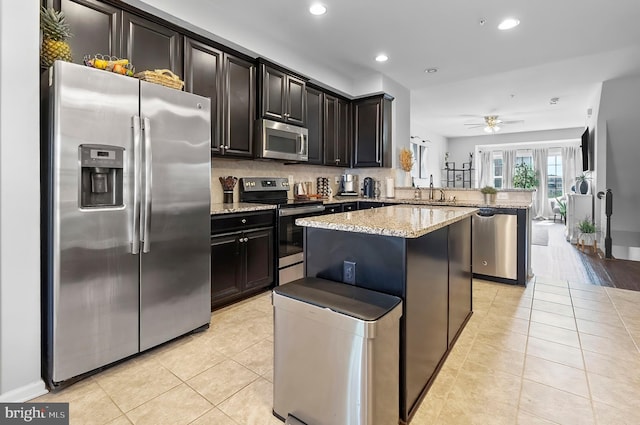 922 S Macon St, Baltimore, MD 21224 - kitchen featuring stainless steel appliances, a peninsula, a center island, light stone countertops, and recessed lighting
