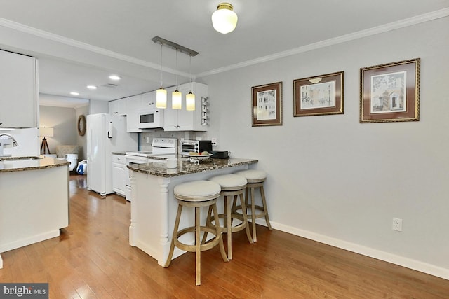1581 Poplar Grove Dr, Reston, VA 20194 - kitchen featuring white appliances, white cabinetry, a breakfast bar area, a peninsula, and wood finished floors