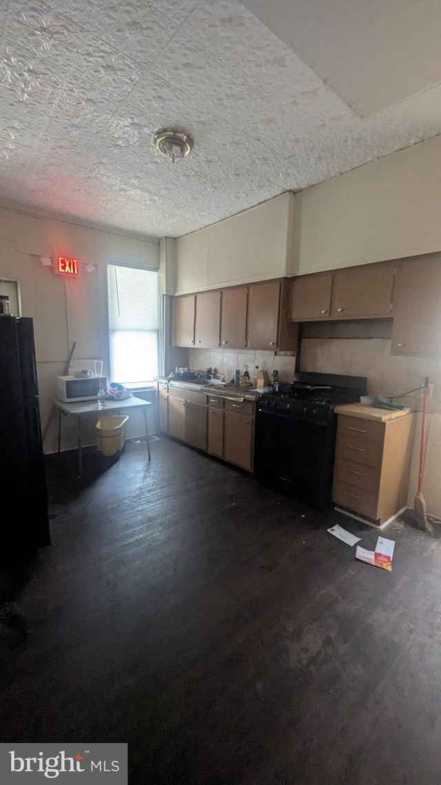 311 Calhoun St, Baltimore, MD 21223 - kitchen featuring black gas range oven, dark wood-style floors, and fridge