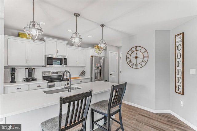 300 Hayward Ct, Pottstown, PA 19464 - kitchen with stainless steel appliances, a breakfast bar area, recessed lighting, wood finished floors, and light countertops