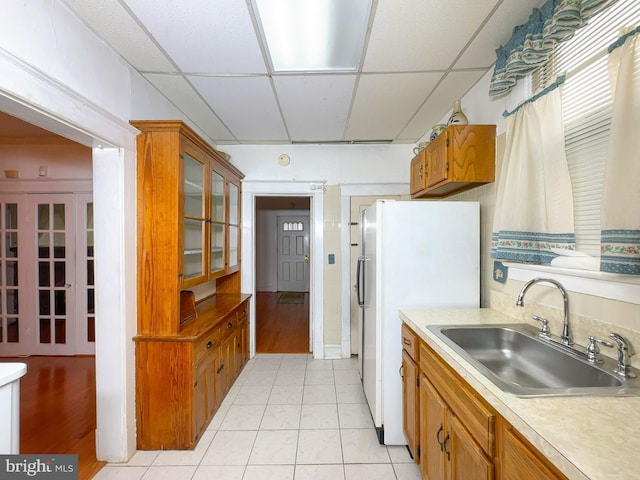 2636 Rhode Island Ave NE, Washington, DC 20018 - kitchen featuring a paneled ceiling, freestanding refrigerator, light countertops, brown cabinets, and light tile patterned floors