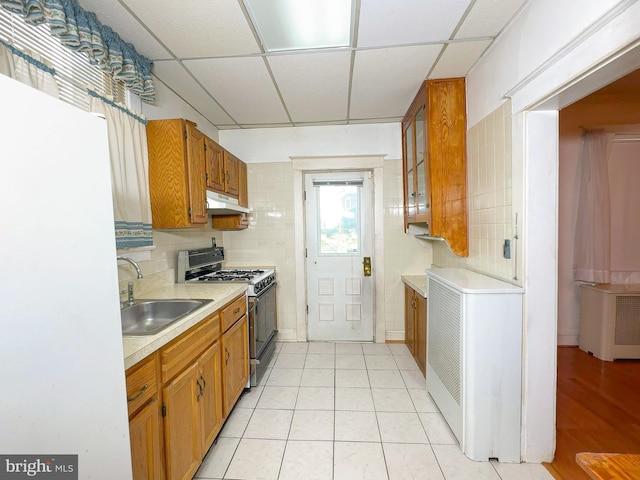 2636 Rhode Island Ave NE, Washington, DC 20018 - kitchen with gas stove, under cabinet range hood, freestanding refrigerator, light countertops, and brown cabinetry