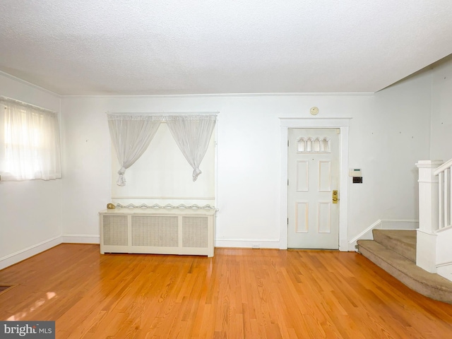 2636 Rhode Island Ave NE, Washington, DC 20018 - unfurnished room with radiator, stairway, light wood finished floors, a textured ceiling, and crown molding