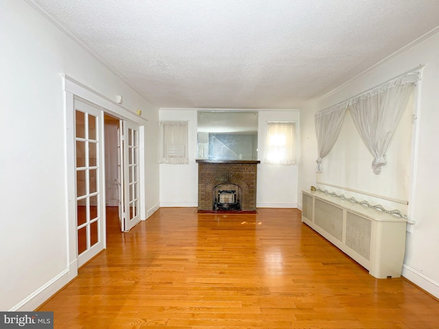 2636 Rhode Island Ave NE, Washington, DC 20018 - unfurnished living room with radiator, a textured ceiling, light wood finished floors, french doors, and ornamental molding