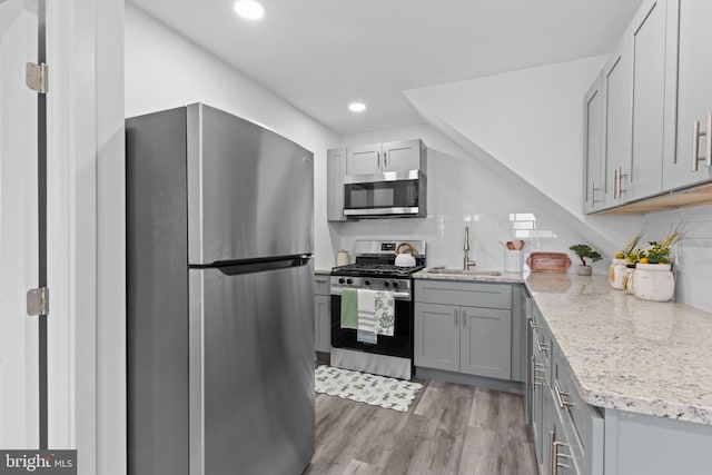 1072 Lakeshore Dr, Camden, NJ 08104 - kitchen with stainless steel appliances, gray cabinetry, light wood-style flooring, tasteful backsplash, and light stone counters