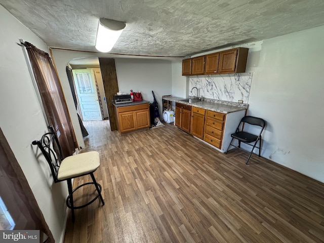226 E Snyder Ave, Lansford, PA 18232 - kitchen with wood finished floors, arched walkways, brown cabinets, and decorative backsplash