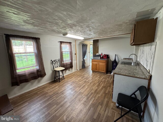 226 E Snyder Ave, Lansford, PA 18232 - kitchen with arched walkways, wood finished floors, dark countertops, a textured ceiling, and brown cabinetry