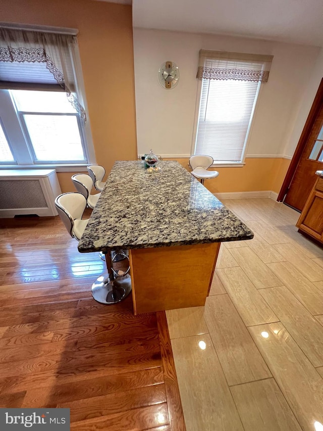 7033 Gillespie St, Philadelphia, PA 19135 - kitchen featuring light wood-style flooring, radiator heating unit, stone counters, and a kitchen island