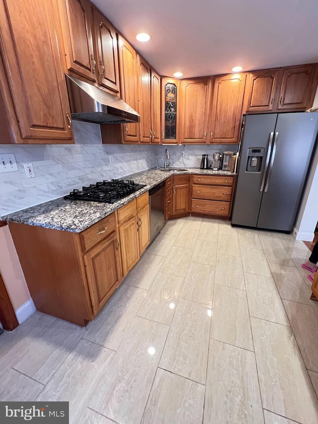 7033 Gillespie St, Philadelphia, PA 19135 - kitchen with stainless steel appliances, under cabinet range hood, brown cabinetry, stone countertops, and light wood-type flooring
