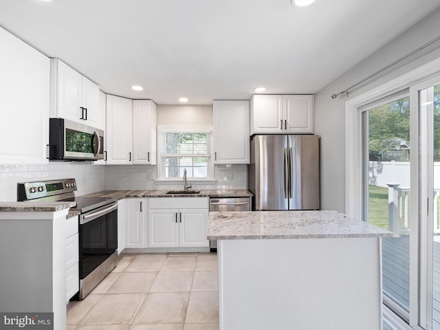 4 Paisley Dr, Wilmington, DE 19808 - kitchen with appliances with stainless steel finishes, backsplash, light tile patterned floors, white cabinetry, and a kitchen island