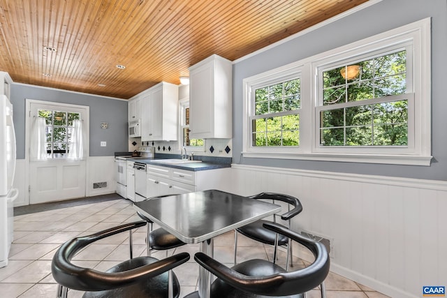2402 Bennington Rd, Charlottesville, VA 22901 - kitchen featuring white appliances, wooden ceiling, light tile patterned floors, a wainscoted wall, and white cabinets