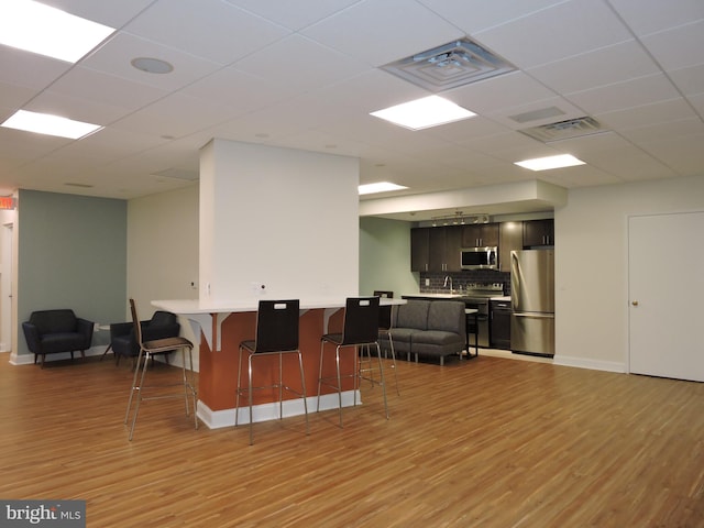 1420 Locust St Unit 20Q, Philadelphia, PA 19102 - kitchen with appliances with stainless steel finishes, a kitchen bar, light wood-style flooring, light countertops, and a drop ceiling
