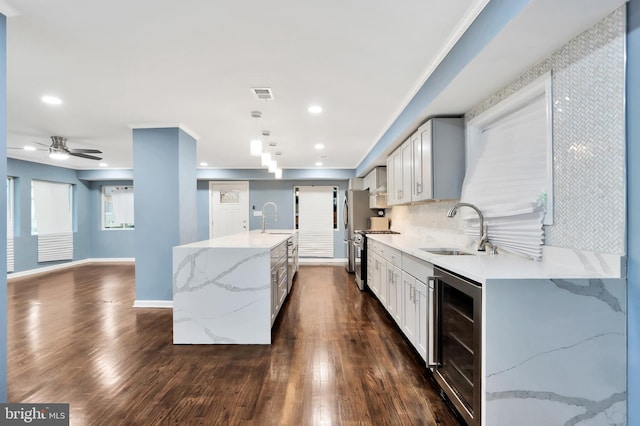 1133 46th St SE, Washington, DC 20019 - kitchen with beverage cooler, stainless steel range oven, light stone countertops, a center island with sink, and dark wood-style floors