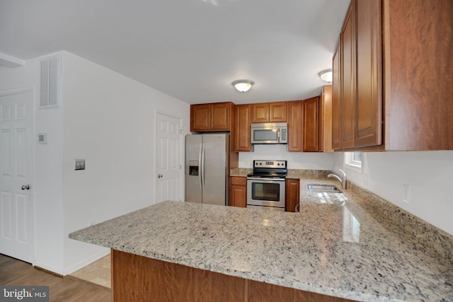 40534 Miss Ettas Way, Leonardtown, MD 20650 - kitchen featuring stainless steel appliances, brown cabinetry, light stone counters, and a peninsula