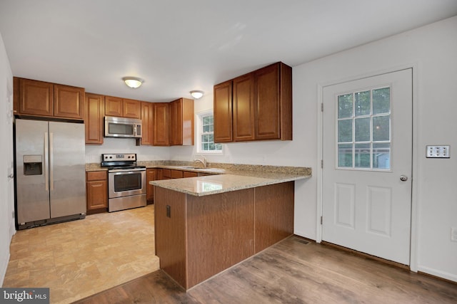 40534 Miss Ettas Way, Leonardtown, MD 20650 - kitchen with stainless steel appliances, brown cabinetry, a peninsula, and light stone counters