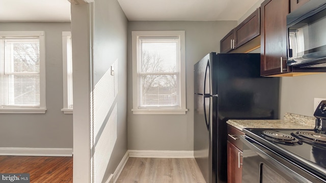 1126 Gleneagle Rd, Baltimore, MD 21239 - kitchen with black appliances, light wood-type flooring, dark brown cabinetry, and plenty of natural light