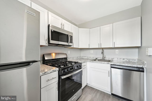 1126 Gleneagle Rd, Baltimore, MD 21239 - kitchen featuring appliances with stainless steel finishes, white cabinetry, light wood-style flooring, and light stone counters