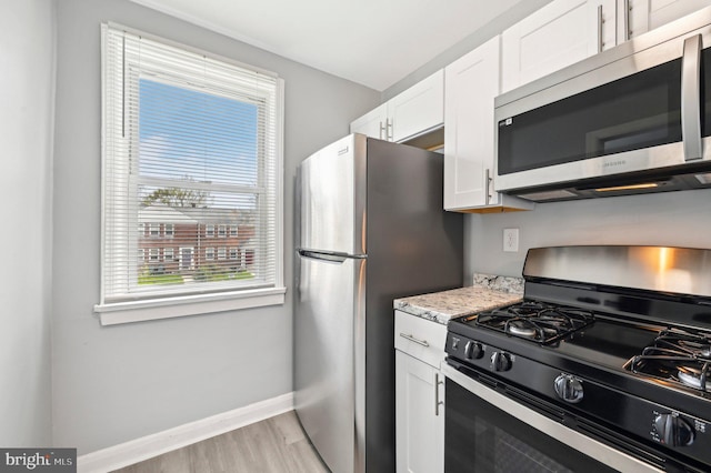 1126 Gleneagle Rd, Baltimore, MD 21239 - kitchen with stainless steel appliances, light wood-style floors, white cabinets, and light stone countertops