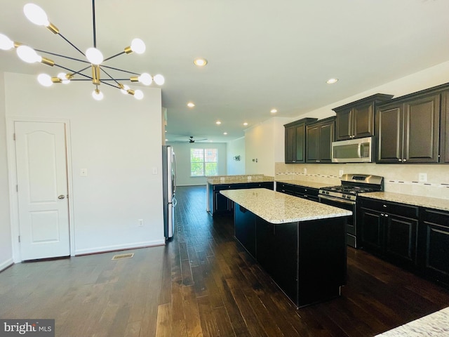 7120 Beaumont Pl, Hanover, MD 21076 - kitchen featuring stainless steel appliances, dark wood-style floors, a peninsula, decorative backsplash, and a kitchen island
