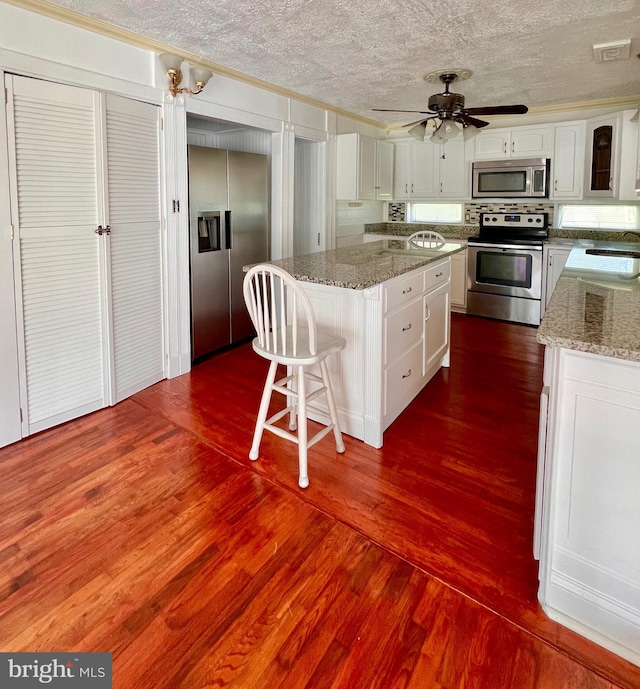 6535 Gravel Branch Rd, Hurlock, MD 21643 - kitchen featuring appliances with stainless steel finishes, a kitchen island, a textured ceiling, dark wood-type flooring, and white cabinets