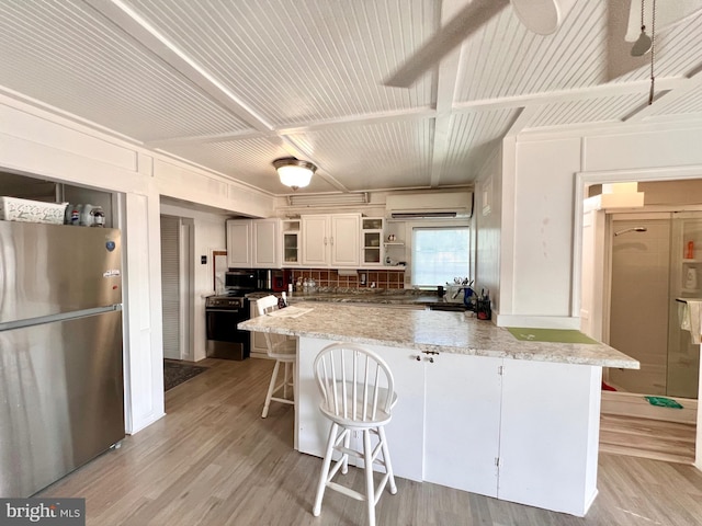 6535 Gravel Branch Rd, Hurlock, MD 21643 - kitchen featuring freestanding refrigerator, a wall unit AC, open shelves, light wood finished floors, and a kitchen bar