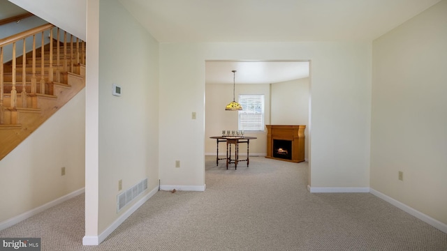 253 Roosevelt St, Bristol, PA 19007 - spare room featuring carpet floors, stairway, and a lit fireplace