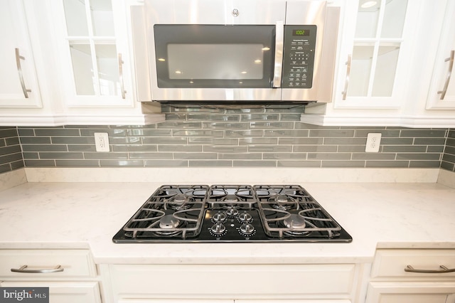 106 Pear Blossom Rd, Stafford, VA 22554 - kitchen with stainless steel microwave, black gas cooktop, white cabinetry, and glass insert cabinets