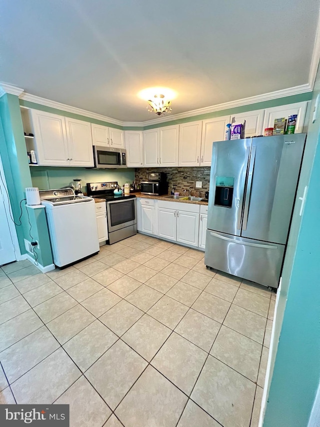9837 Buckner Rd, Manassas, VA 20110 - kitchen featuring appliances with stainless steel finishes, washer / dryer, white cabinets, light tile patterned floors, and ornamental molding